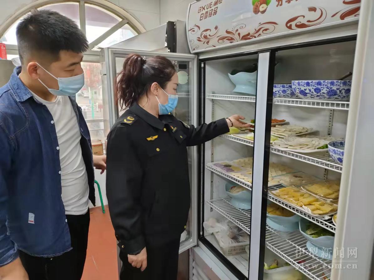 执法人员检查餐饮后堂食品原材料.jpg